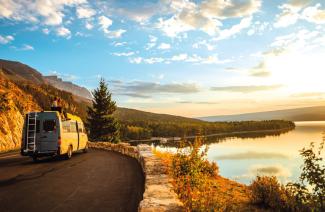 Campervan auf einer Bergstraße am See bei Sonnenuntergang